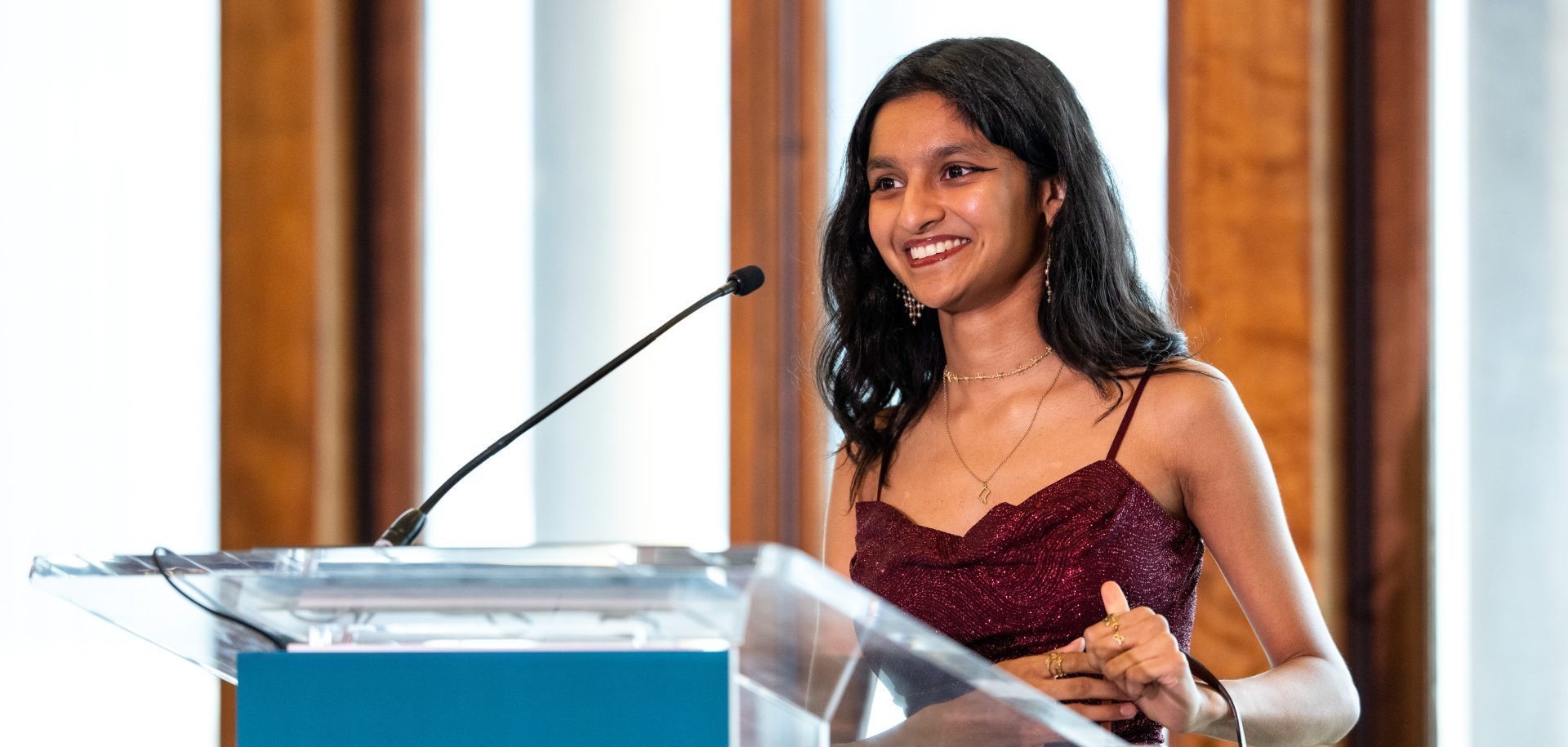 Smiling woman speaking at podium.